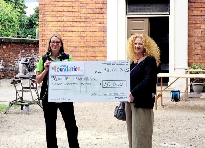 Two smiling women hold a big cheque during a commemorative ceremony to hand over a grant.